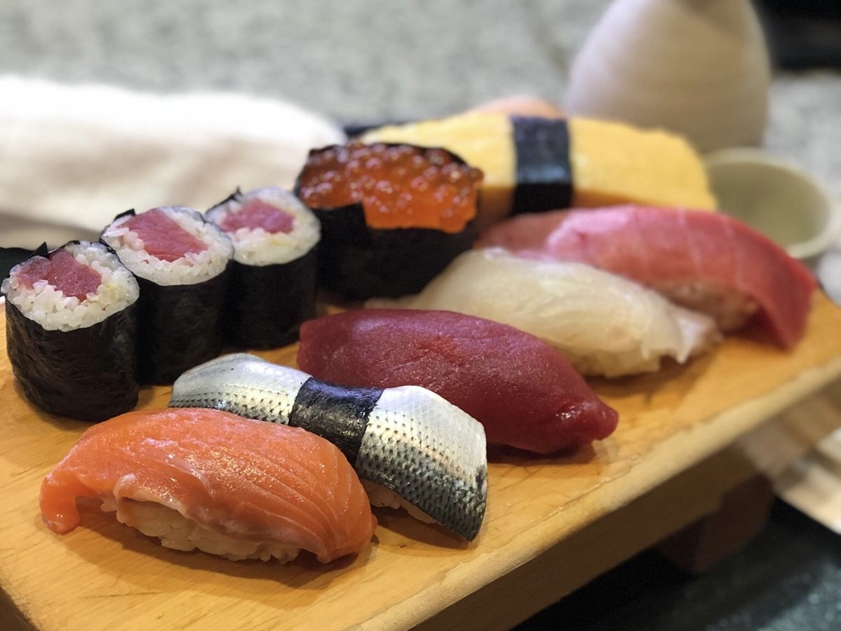 Omakase sushi board — nigiri, maki and ikura on warm wood, Japan