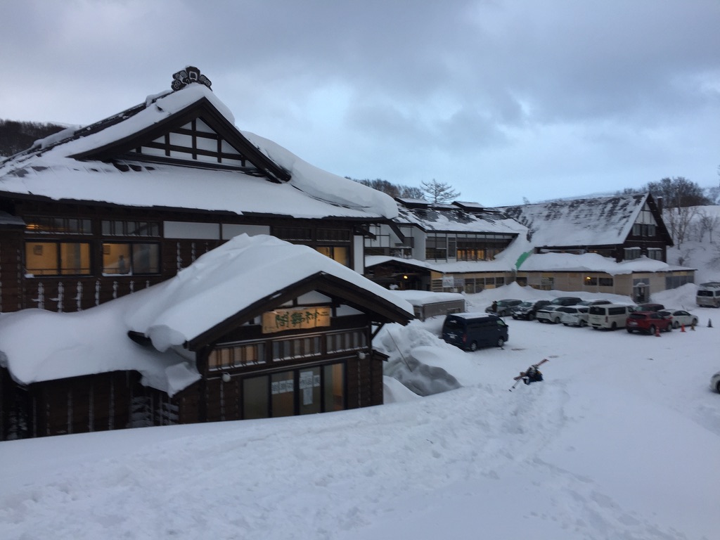Snow-buried traditional ryokan glowing against blue winter dusk, Japan snow country